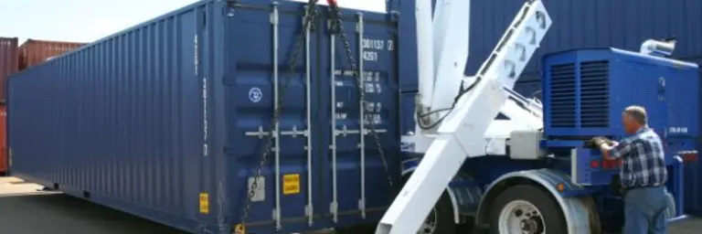 man delivering a blue shipping container with a small crane