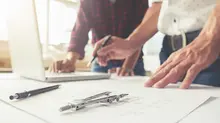 two men with blueprint and laptop