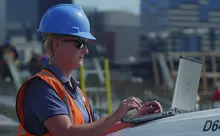 female in hardhat on construction site with laptop