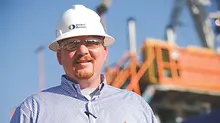 man in ppe next to industrial plant