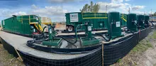 green tanks and pumps handling water discharge at a jobsite on a clear day