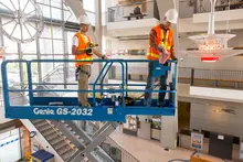 Two workers on a scissor lift inside of a building